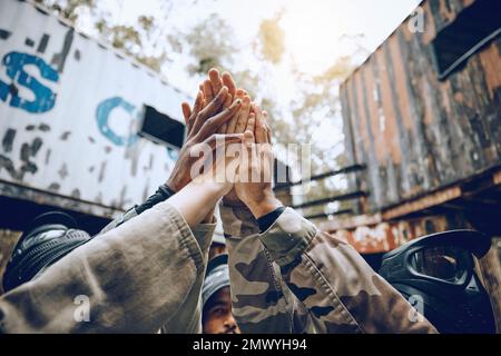 Paintball, Gruppe und High Five für Partnerschaft, Feier und extremen Sporterfolg, Sieg für Spielzeit oder Tor. Teambildung, Freunde oder Stockfoto