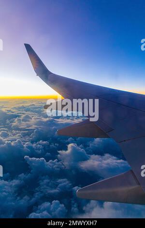 Blick aus dem Passagierfenster eines Boeing 737-Flugzeugs, das über die Wolken bei Sonnenuntergang fliegt. Stockfoto