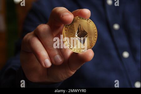 Ethereum-ETH-Kryptowährung-Goldmünze im handabstrakten Konzept Stockfoto