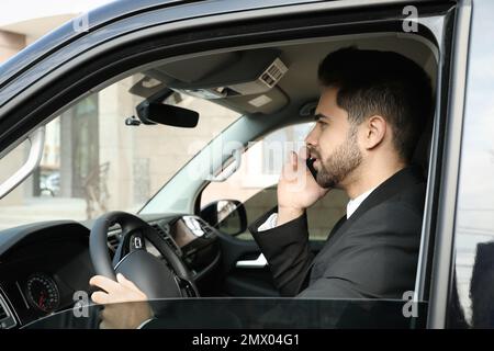 Attraktiver junger Mann, der während der Fahrt mit dem Smartphone spricht Stockfoto