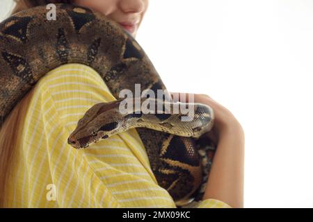 Junge Frau mit Boa Constrictor auf weißem Hintergrund, Nahaufnahme. Exotisches Haustier Stockfoto