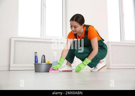 Professioneller junger Hausmeister, der den Boden im Innenbereich poliert. Reinigungsservice Stockfoto