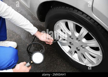 Mechaniker, der den Reifendruck im Autorad an der Tankstelle überprüft, Schließung Stockfoto