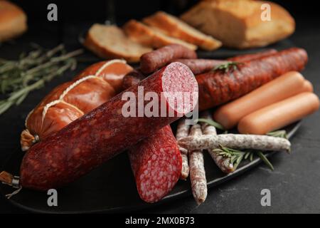 Verschiedene leckere Würstchen auf schwarzem Tisch, Nahaufnahme Stockfoto
