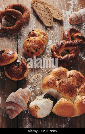 Von oben Scheiben türkisches Brot serviert auf einem unordentlichen Holztisch mit verschiedenen Arten von süßem Gebäck in der hellen Küche Stockfoto