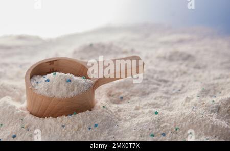 Ein Haufen antibakterielles Seifenpulver für die tägliche Wäscherei mit einem hölzernen Messbecher, der auf einem dreckigen Tisch im Lichtstudio platziert wird Stockfoto