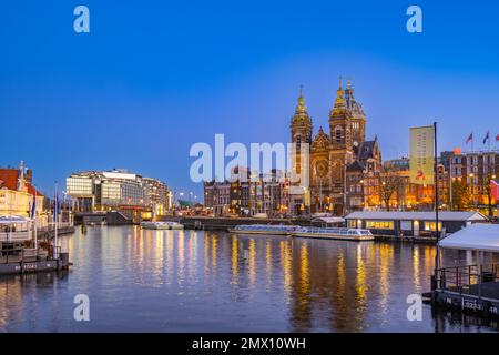 Blick über den Hafen von der Centraal Station IJzijde über den Hafen in Richtung St. Nicholas Kirche und Prins Hendrikkade Straße in der Abenddämmerung Stockfoto