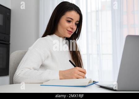Fokussierte junge Studentin, die sich auf die Prüfungen vorbereitet und Webinare ansieht. Stockfoto