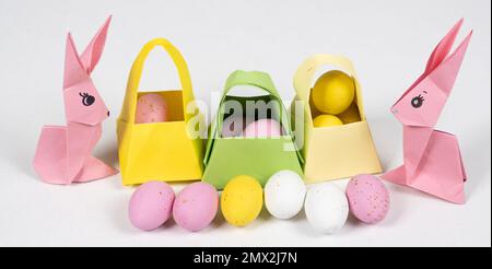 Zwei pinkfarbene Osterhasen aus Papier, Origami-Handwerk und Eierkörbe, ein langes Banner Stockfoto