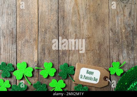 Kleeblätter, Anhänger und Platz für Text auf Holztisch, flache Verlegung. St. Patrick's Day-Feier Stockfoto
