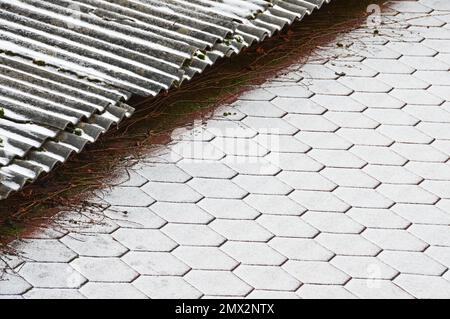 Der Rand von zwei Dächern mit verschiedenen Beschichtungen, die mit frischem Schnee bedeckt sind. Selektiver Fokus Stockfoto