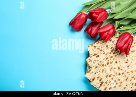 Matzen und Blumen auf hellblauem Hintergrund, flach liegend mit Platz für Text. Passover (Pesach) Seder Stockfoto