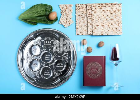 Flache Laienzusammensetzung mit symbolischen Pesach-Elementen (Passover Seder) auf hellblauem Hintergrund Stockfoto