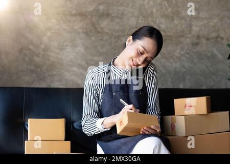 Start Small Business KMU, Unternehmer Eigentümer mit Smartphone oder Tablet erhalten und prüfen online kaufen Shopping um Vorbereitung Pack Stockfoto