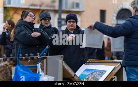 Drei Erwachsene Frauen kaufen ein Gemälde an einen Künstler, der seine Werke auf der Straße in rom, italien, verkauft. Stadtleben-Konzept Stockfoto