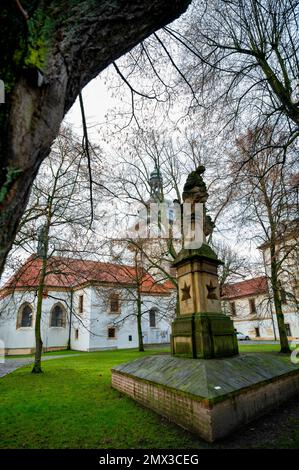 Schlosspark mit Statue der Jungfrau Maria der Krankenschwester und der Geburtshkirche der Jungfrau Maria in Benatky nad Jizerou, Tschechische republik. Stockfoto