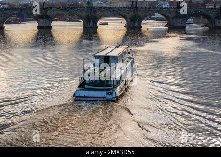 Das Boot fährt die Moldau hinunter zur Karlsbrücke in Prag, Tschechische republik. Schönes Licht, Herbst. Besichtigungsrundfahrt. Stockfoto