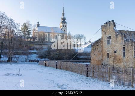 Europa, Luxemburg, Koerich, Grevenschlass (Schloss Koerich) im Winter Schnee mit Elglise Saint-Remi (Kirche) dahinter Stockfoto