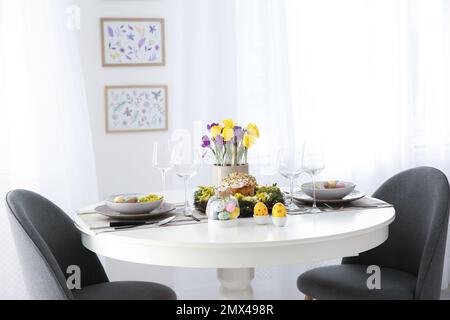 Festlicher Ostertisch mit wunderschönen Blumen und Eiern im Innenbereich Stockfoto