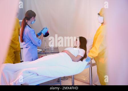 Professionelle Sanitäter untersuchen Patienten mit Virus in der Quarantänestation Stockfoto
