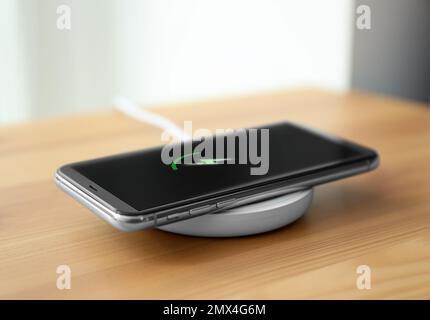 Smartphone-Aufladung über kabelloses Pad im Zimmer Stockfoto