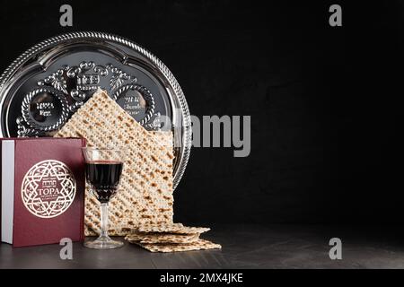 Symbolische Pesach-Elemente (Passover Seder) auf schwarzer Tabelle, Platz für Text Stockfoto