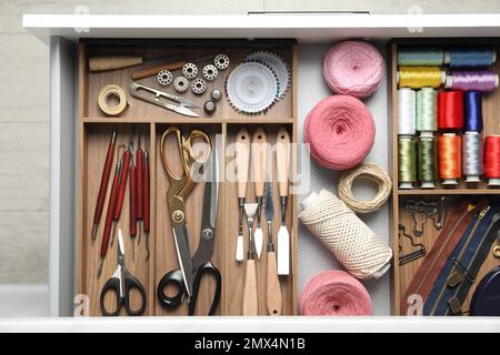 Nähzubehör in offener Schreibtischschublade, Draufsicht Stockfoto