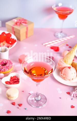 Romantischer süßer Desserttisch mit einem Glas Rosa Wein, Waffeln, Donut, Eis, Makronen, lutscher, Süßigkeiten. Valentinstag-Konzept. Stockfoto