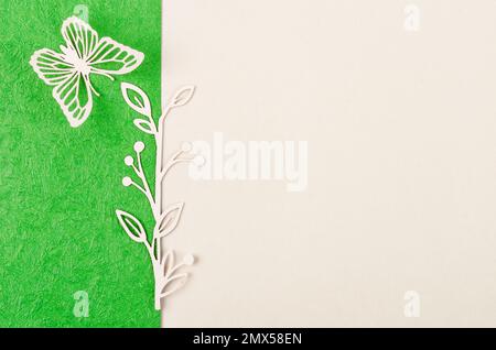 Schmetterling und Blume aus geschnitztem Papier oder Schnitt auf grünem und gelbem Hintergrund mit leerem Platz für Ihren Text oder Ihre Nachricht. Stockfoto