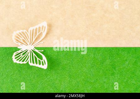 Schmetterling aus geschnitztem Papier oder Schnitt auf grünem und gelbem Hintergrund mit leerem Platz für Ihren Text oder Ihre Nachricht. Stockfoto