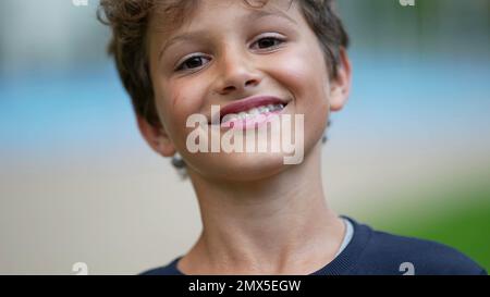 Ein glücklicher Junge, das Porträt, die Nahaufnahme, die draußen lächelt. Ein gutaussehender männlicher Junge, der eine Zahnspange trägt und in die Kamera schaut Stockfoto