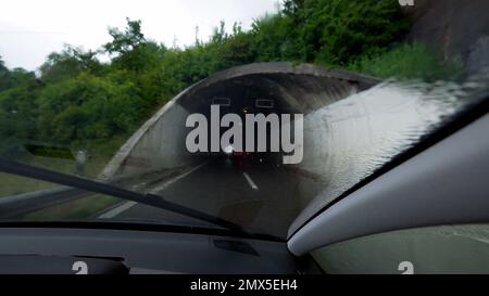 Das Auto fährt an regnerischen Tagen in den Straßentunnel. Bei schlechtem Wetter fährt die Windschutzscheibe Stockfoto