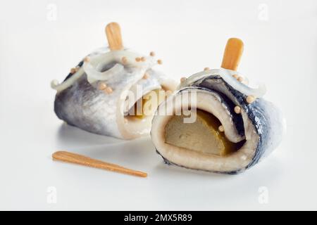 Nahaufnahme von köstlichen Rollmops aus Heringsfilet und eingelegten Gurken mit Zwiebeln auf weißem Tisch Stockfoto