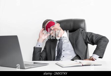 Müder Arbeitgeber entspannt sich in der Schlafmaske am Arbeitsplatz Stockfoto