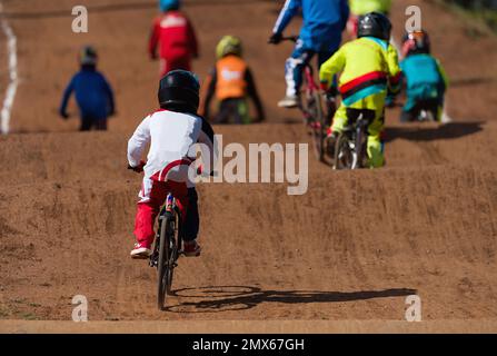 BMX-Fahrer, die in der Kinderklasse auf der Geländestrecke gegeneinander antreten Stockfoto