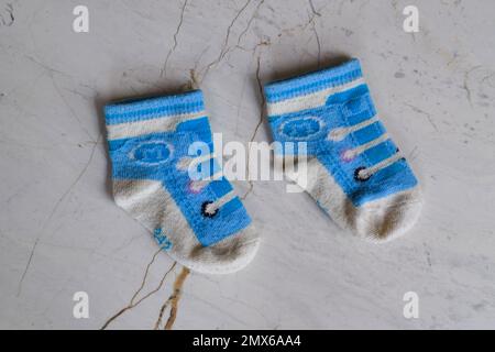 Ein Paar kleine Babysocken auf Keramikhintergrund. Blaue Babysocken Stockfoto