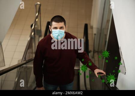 Mann trägt medizinische Maske auf Rolltreppe im Einkaufszentrum. Gefährlicher Virus Stockfoto