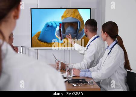 Ärzteteam mit Videoprojektor während der Coronavirus-Konferenz in der Praxis Stockfoto