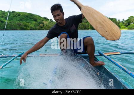 Junger philippinischer Fischer, der Fischernetze auf seinem Boot vorbereitet, philippinische Inseln, echte Menschen, Lebensstil Stockfoto