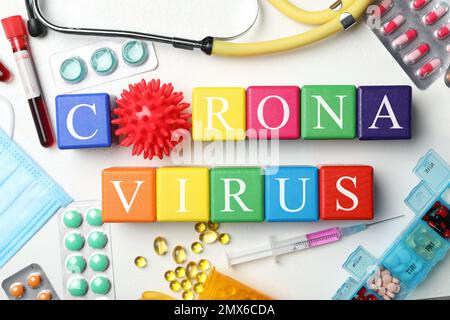 Würfel mit Phrase CORONA VIRUS und Medikamente auf weißem Hintergrund, flach liegend Stockfoto