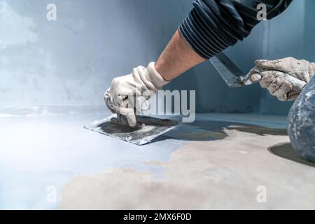 Verteilen der Isolierung auf dem Beton mit einer Kelle Stockfoto