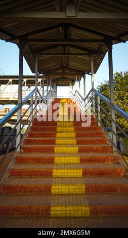 Vom Bahnhof aus geht man über die Treppe zur Brücke, von innen aus blickt man auf den Bahnhofskorridor, von einer Treppe über die Brücke bei einer ländlichen Bahnstunde Stockfoto