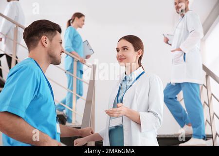 Eine Ärztin, die mit einer Kollegin auf der Treppe in der Klinik spricht Stockfoto