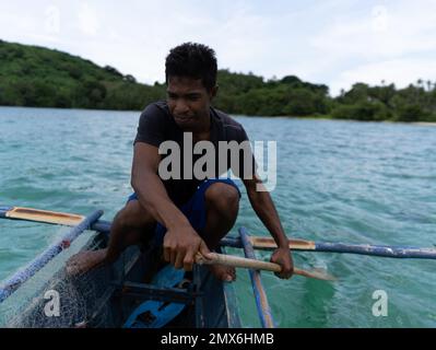 Junge asiatische Fischer rudern auf einem Boot in einem tropischen Meer auf den philippinen Stockfoto