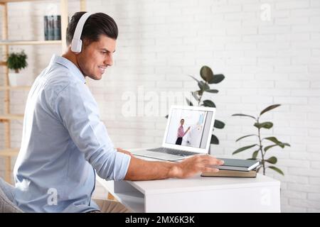 Ein Mann, der sich drinnen ein Video am Schreibtisch ansieht. Online-Lernen Stockfoto