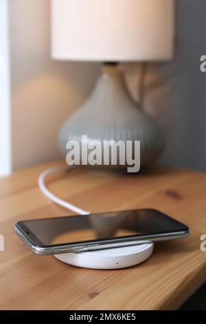 Smartphone-Aufladung über kabelloses Pad im Zimmer Stockfoto