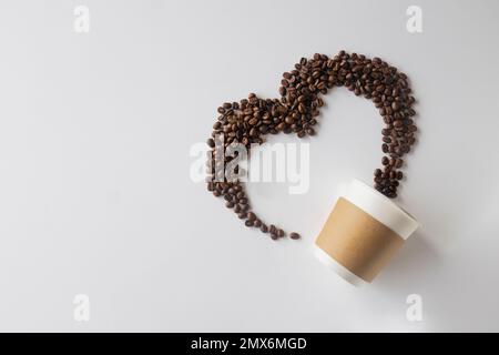 Kaffeeliebhaber. Draufsicht auf Pappbecher und Kaffeebohnen in wunderschöner Herzform auf weißem Hintergrund. Festliche Karte zum Valentinstag. Oben vi Stockfoto