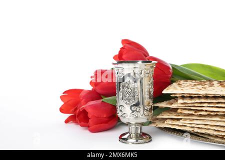 Passover-Matzen, silberner Becher und Blumen auf weißem Hintergrund. Pesach-Feier Stockfoto