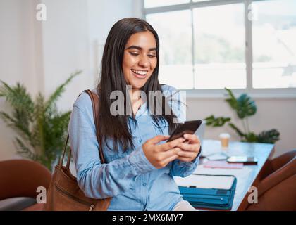 Junge Geschäftsfrau kommt früh ins Büro und schreibt SMS, während sie wartet Stockfoto