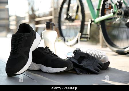 Fahrradhandschuhe, Schuhe und Flasche im Freien an sonnigen Tagen Stockfoto